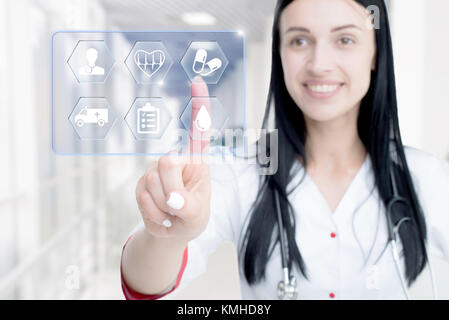 Young attractive woman doctor touching icon of media screen. Concept of innovative technologies in medicine. Stock Photo