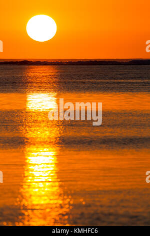 The golden light of the setting sun reflecting in the calm water of the lagoon at Le Morne in Mauritius, Africa. Stock Photo