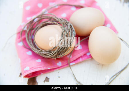 three eggs on the table on a rose napkin. Stock Photo