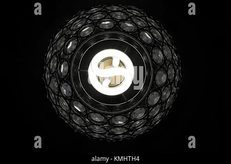 Daylight balanced energy saving light bulb viewed from underneath set in an ornate glass shade, the image was taken using the Spot metering mode on the Stock Photo