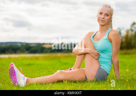 Fit blonde woman stretching outdoor on the grass Stock Photo