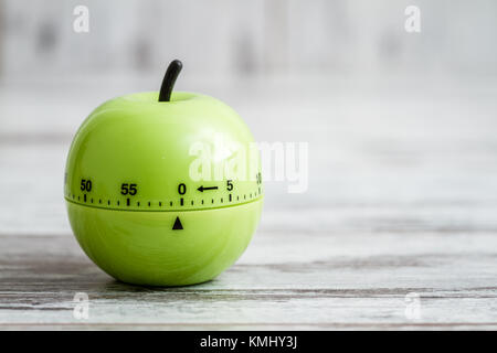 Green kitchen cooking timer with apple shape on white wooden background Stock Photo