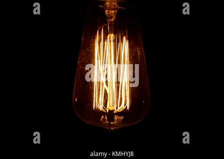 Retro style lightbulb illuminated against a dark background Stock Photo