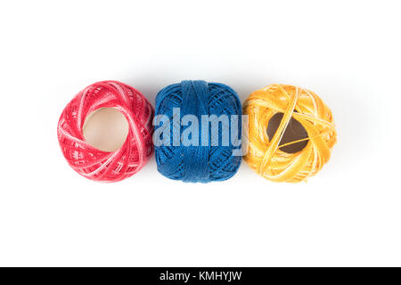 Three colored sewing threads on a white background, yellow, blue and red thread Stock Photo