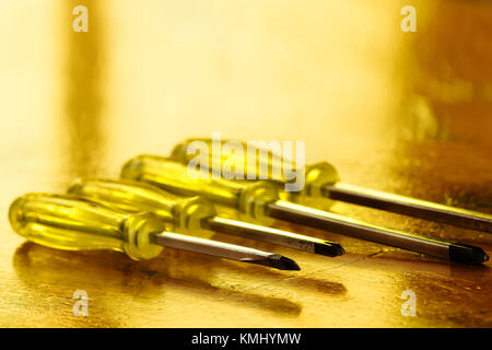 Horizontal photo of a yellow screwdrivers set on a wood table. Yellow background Stock Photo