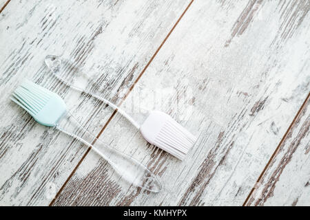 Silicone cooking brushes with transparent handles on white wooden background Stock Photo