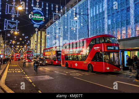 London Buses line up outside John Lewis department Store on London's Oxford St at Christmas time under the Oxford St Christmas Lights.London ,UK Stock Photo