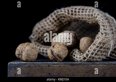 Peanuts in a natural bag. A sack of nuts on an old dark wooden table. Black background Stock Photo