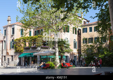 Daily living in Venice  with local Venetians relaxing in Campo San Giacomo dell Orio, Santa Croce  in the shade of leafy trees in spring Stock Photo