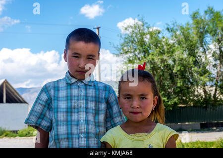 UGUT, KYRGYZSTAN - AUGUST 16: Siblings, brother and a sister posing with serious facial expression. Ugut is a remote village in Kyrgyzstan. August 201 Stock Photo