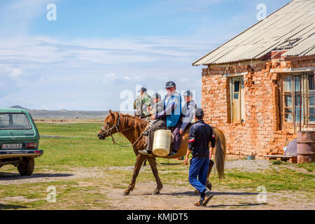 KEL-SUU, KYRGYZSTAN - AUGUST 13: Man and kids riding a horse in a remote village in Kyrgyzstan. August 2016 Stock Photo