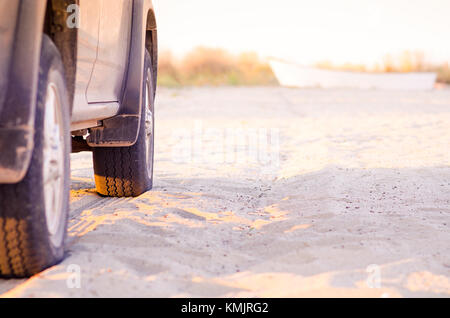 Pickup truck on the beach sand with boat in background Stock Photo