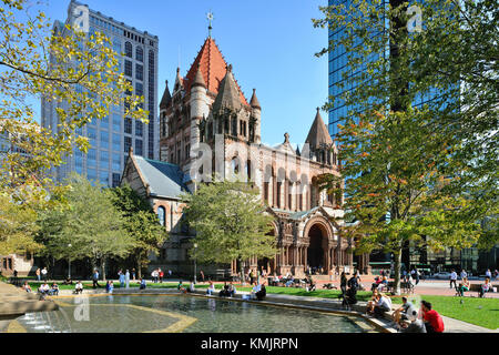 Trinity Church, a national historic landmark building in Back Bay, Boston.  People hanging around the Copley Square fountain in a sunny day of fall. Stock Photo
