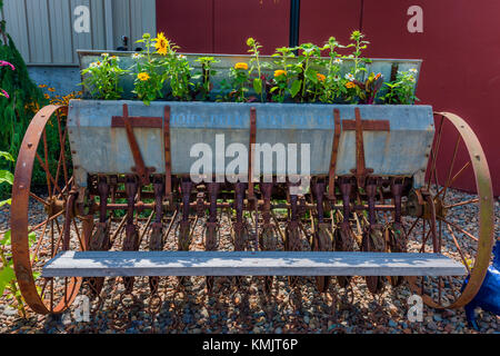 McMinnville, Oregon, USA - August 13, 2016:  Obsolete John Deer tractor implement planter, now being used as a flower planter. Stock Photo