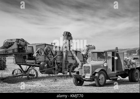 McMinnville, Oregon, USA - August 13, 2016:  Black and white of an old flat bed truck parked by an old grain harvester. Stock Photo
