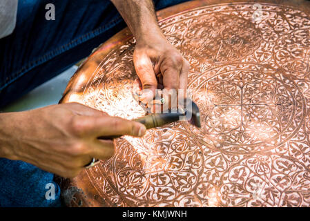 Senior craftsman,tinsmith,working with hammer during hand stamping or engraving decoration pattern on metal plate.Copper master, hands detail of craft Stock Photo