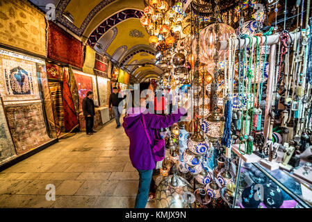 Unidentified Tourists visiting and shopping in the Grand Bazaar in Istanbul. Interior of the Grand Bazaar with souvenirs on the foreground.Istanbul, T Stock Photo