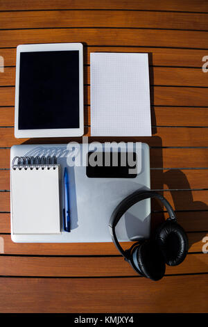 Business set - empty blank white notepad on a spiral with wind-blown sheet of paper, metallic laptop, blue ballpoint pen, black mobile phone, headphon Stock Photo
