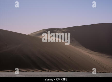 A lone climber heads for the top of the dunes at sunrise in Dead Vlei, Namibia Stock Photo