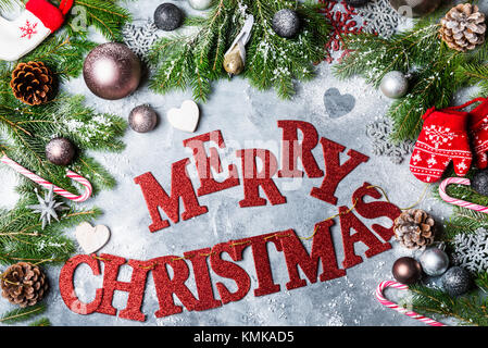 Christmas Frame made from Xmas Tree Branches, Baubles, Pine Cones, Candy Canes, Mittens and Snowflakes on the Grey Background. Also there are Red Lett Stock Photo