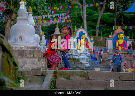 KATHMANDU, NEPAL OCTOBER 15, 2017: Unidentified children sitting at outdoors close to Swayambhu, an ancient religious architecture atop a hill west of Kathmandu city. It is also known as Monkey Temple Stock Photo
