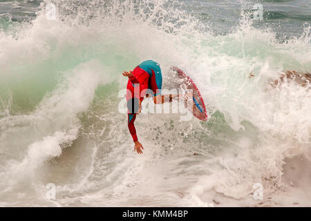 Losing his balance, a surfer riding the waves on a skimboard is about to wipeout in Laguna Beach, CA. Stock Photo