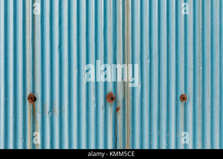 Light blue corrugated metal wall with rusty bolts and streaks of rust Stock Photo