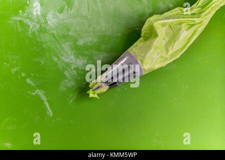 Green frosting pastry bag on a green mat. Stock Photo