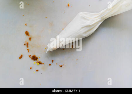 Frosting pastry bag with bread crumbs on cutting mat. Stock Photo