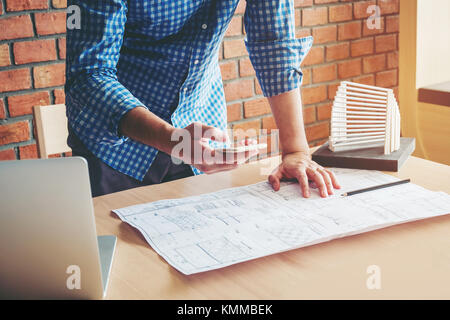 Architect or engineer using smart phone working in office on blueprint. Architects workplace Stock Photo