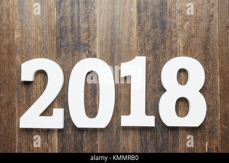 Wooden and painted with white color digits 2018 on rustic rough wooden background as concept of New Year and Christmas.Top view. Stock Photo