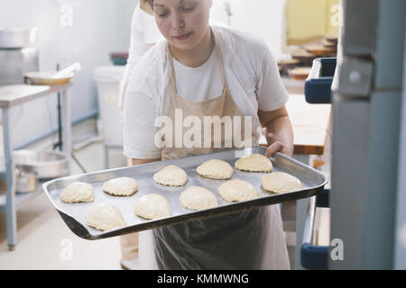 Cook puts pies into stove for baking Stock Photo