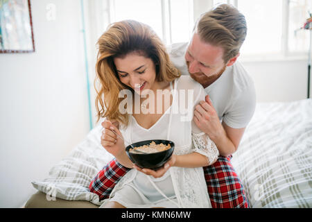 Beautiful happy couple waking up smiling in bedroom Stock Photo