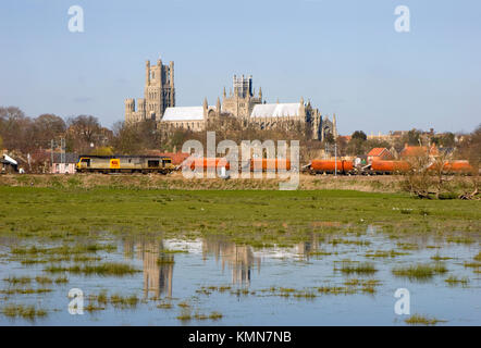 A class 60 diesel locomotive number 60099 passes Ely Cathedral with a train of empty RMC stone hopper wagons. Stock Photo