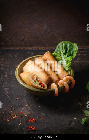 Fried spring rolls with vegetables and shrimps, served in ceramic bowl over black background. Stock Photo