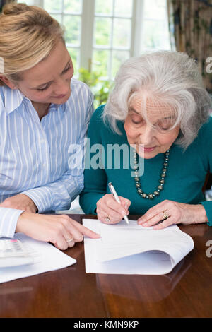 Woman Helping Senior Neighbor With Paperwork Stock Photo