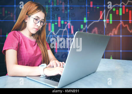 asian businesswoman sitting amd working Laptop Stock market exchange information and Trading graph Stock Photo