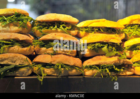 a pile or stack of filled bread rolls for sale on a street food stall at londons famous borough market in southwark. Salad and meat filled rolls. Stock Photo
