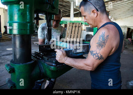 Men using a drill in a factory in Cienfuegos, Cuba Stock Photo