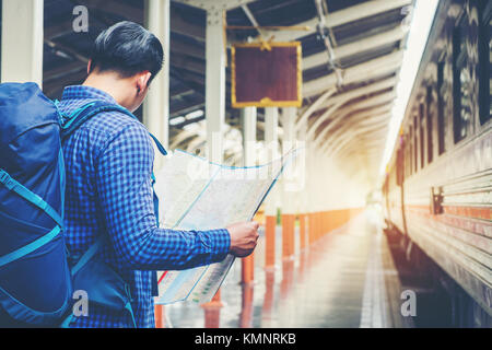 Tourist backpacker using map to travel at train station Stock Photo