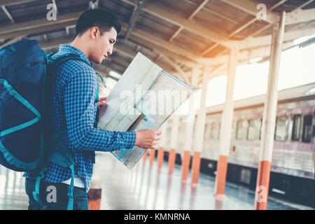 Tourist backpacker using map to travel at train station Stock Photo