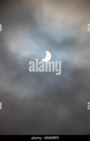 Partial eclipse of the sun seen through clouds Stock Photo