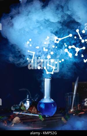 Potion bottle with steam and constellations. Still life with magical equipment and starry sky. Astronomer workplace Stock Photo