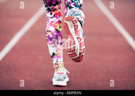 Close up of girls feet in sneakers and tights, running on a special running track with a soft finish. Stock Photo