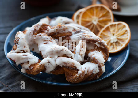 Bavarian cream puff with crushed hazelnuts and slices of dried oranges on a blue plate. A dark background. Stock Photo