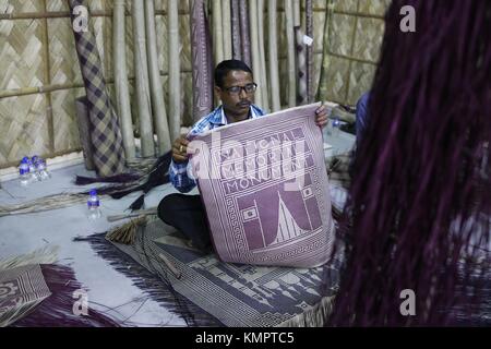 Dhaka, Bangladesh. 9th Dec, 2017. A craftsman shows a Shital pati (a traditional mat made of materials from murta plants) to customar at an exhibition on Shitol Pati at the national Museum of Bangladesh. Credit: Md. Mehedi Hasan/ZUMA Wire/Alamy Live News Stock Photo