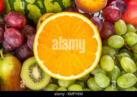 Fresh Orange on a background of different fruits and grapes Stock Photo