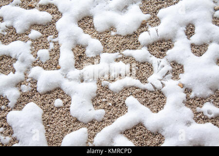 GRAVEL BACKGROUND COVERED BY SNOW WITH BIRD FOOTSTEPS Stock Photo