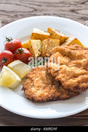 Portion of schnitzel with garnish on the wooden table Stock Photo