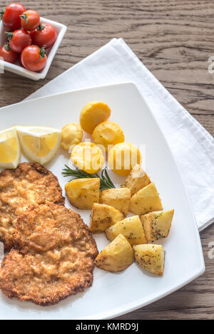Portion of schnitzel with garnish on the wooden table Stock Photo
